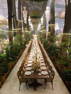 a long table set up with plates and place settings for dinner in a garden setting