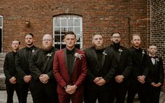 a group of men standing next to each other in front of a red brick building