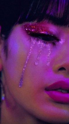 a close up of a woman's face with pink makeup and glitter on her eyes