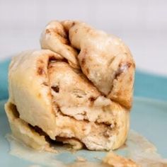 two cinnamon rolls stacked on top of each other in front of a blue plate with white frosting