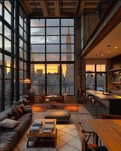 a living room filled with lots of furniture and large windows overlooking the city at sunset