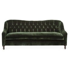 a green velvet couch sitting on top of a white floor