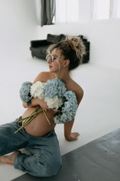 a woman sitting on the ground with flowers in her lap