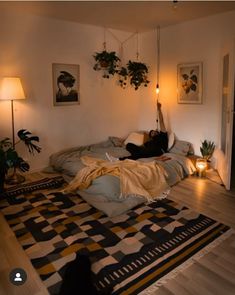 a person laying on top of a bed in a room next to two lamps and plants