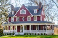 a large red house with white trim on the front porch and wraparound porches