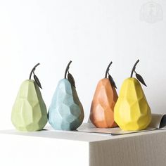 three different colored pears sitting on top of a white shelf next to each other