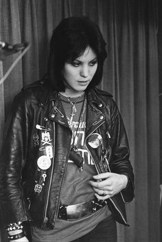 a black and white photo of a person wearing a leather jacket with patches on it