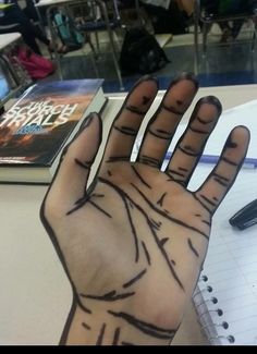 a person's hand with lines drawn on it in front of a notebook and pen