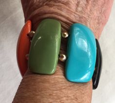 "Mod, groovy 60s statement bracelet with multi color flat pieces of polymer or plastic cut to look like stones. It's hard to measure because it's a stretch elastic bracelet, but it fits me a little loose and my wrist is 7\". (When I put it a little higher on my arm where it's 8\" it fits firmly there.) The stones are 2\" wide and have gold beads between them. Also, please take a look at my storefront at: https://www.etsy.com/shop/FabFinds42?ref=seller-platform-mcnav I have a wide selection of on Mid Century Clock, Diy Earrings Polymer Clay, Mod 60s, Orange Bracelet, Color Bracelet, Earrings Polymer, Retro Clock, Faceted Gems, Coral Bracelet