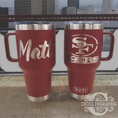 two red yeti mugs sitting next to each other in front of a cityscape