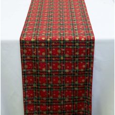 a red table runner with green and gold plaid pattern on it, along with a white table cloth