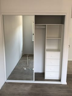 an empty room with white closets and drawers in the middle, including one door open