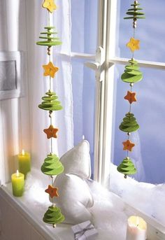 a window sill with candles and decorations hanging from it's sides, in front of a window