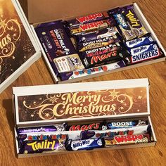 two boxes filled with christmas candy sitting on top of a wooden floor next to each other