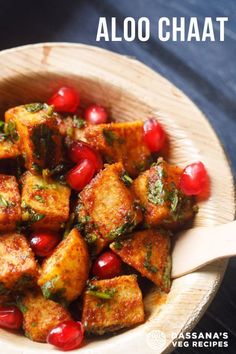 a wooden bowl filled with tofu and pomegranate on top of a table