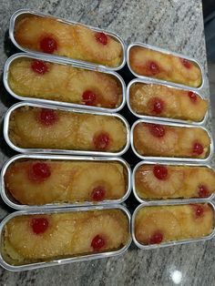 six tins filled with pineapple upside down cake slices sitting on a marble counter top