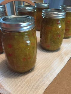 four jars filled with pickles sitting on top of a table