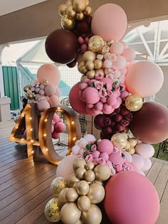 balloons are arranged in the shape of letters and numbers on a wooden floor with lights around them