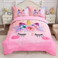 a pink bed with an unicorn face and flowers on the comforter is in front of a white chair