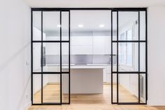 an empty room with glass doors leading to the kitchen