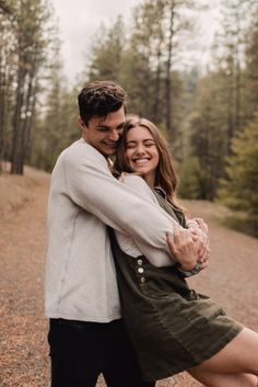 a man and woman hugging in the woods