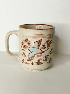 a coffee mug with two birds painted on the outside and inside, sitting on a white surface