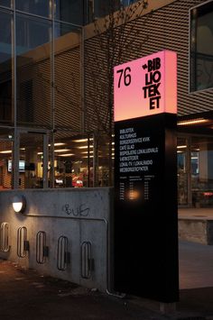 a tall building with a sign on the side of it's front entrance at night