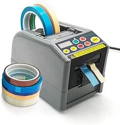 a machine that is next to some tape and a cup on the ground with it's lid open