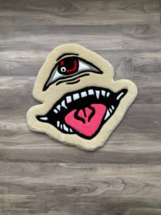 a close up of a rug on a wooden floor with an evil face and tongue