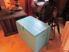 a blue chest sitting on top of a hard wood floor next to a table and chair