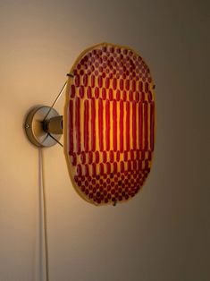 a red and yellow object is hanging on the wall next to a light fixture in a room