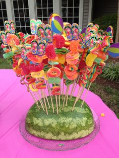 there is a watermelon on the table with some candy sticks in it and flowers