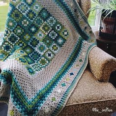 a crocheted granny blanket sitting on top of a chair next to a potted plant