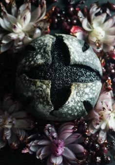 a cross on top of a rock surrounded by flowers