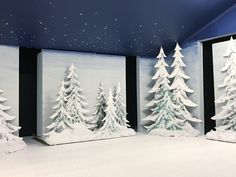 three snow covered trees in front of two black and white doors with stars on the ceiling