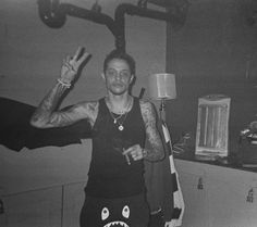 a man standing in a kitchen with his hand up to the camera and wearing a shark costume