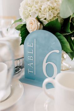 the table numbers are blue and white with flowers in vases next to each other