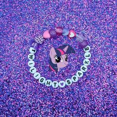 a pony bracelet with beads and charms on it's end is laying on the ground