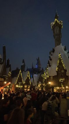 a crowd of people standing in front of a building with christmas lights all around it