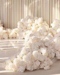 a bunch of white flowers sitting on top of a table next to a wall covered in curtains