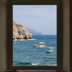 there is a boat out on the water in the ocean from an open window that looks out onto another body of water