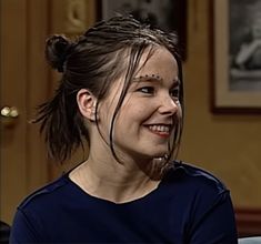 a smiling woman with braids on her hair sitting down and looking at the camera