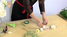 a woman is making flowers on a table