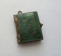 a small green square shaped object with writing on the front and back side, sitting on a white surface