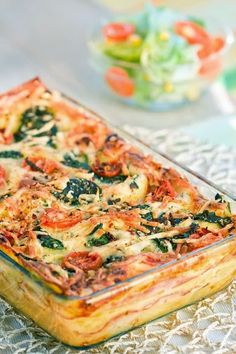 a casserole dish with tomatoes, spinach and cheese in it on a table