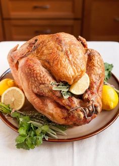 a roasted turkey on a plate with lemons and parsley