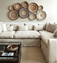 a living room filled with lots of furniture and plates hanging on the wall above it