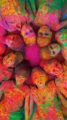 a group of children covered in colored powder are standing together and looking up at the camera