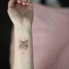 a cat tattoo on the wrist of a woman's left arm and right hand