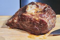 a piece of meat sitting on top of a cutting board next to a knife